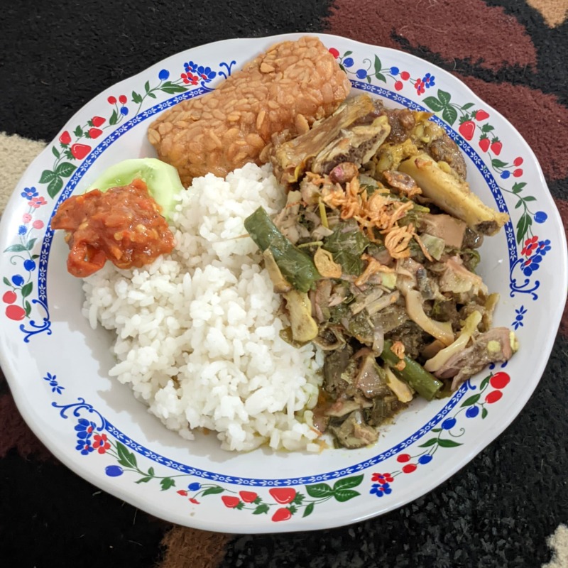 Nasi Gudug?
Bagi warga kecamatan Arjasa, hidangan ini sangat spesial karena hanya ada se tahun sekali saat bulan Suro (menurut budaya dan adat kejawen) saja. Di bulan “Kemerdekaan” ini, Nasi Ghudug hadir setiap hari dari tanggal 4 – 31 Agustus 2024 di Java Lotus Hotel. Keren kan?
Nasi Gudhug adalah makanan unik dengan daun “porpoh”nya, diimbangi rempah- rempah ber jinten.
